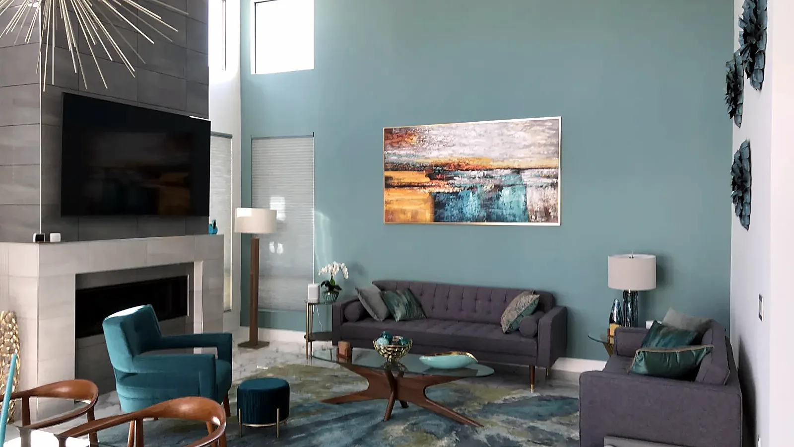 Living room with a teal accent wall and a large canvas hung over the fireplace side