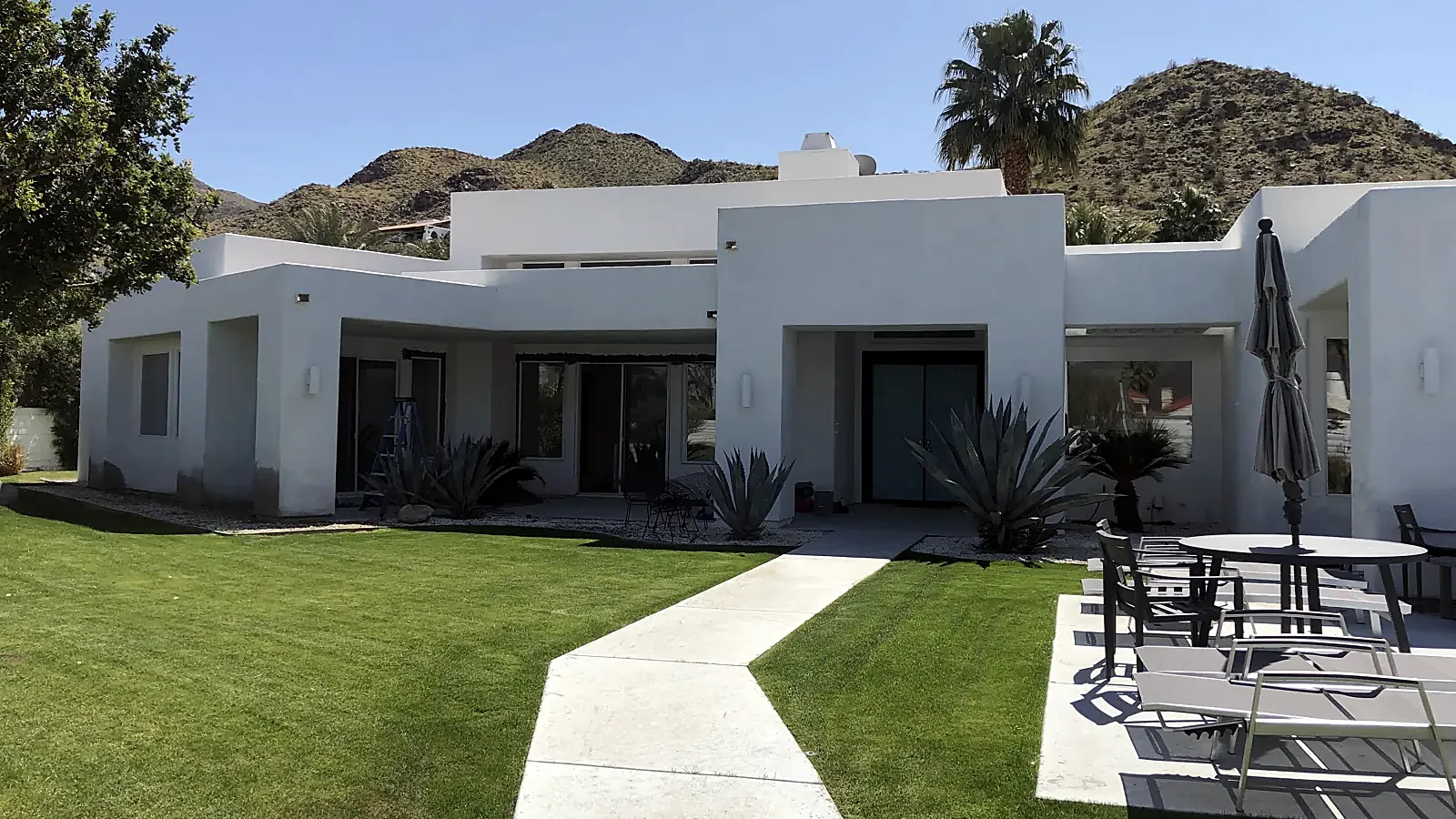 White desert-modern home with new glass doors opening onto the lawn