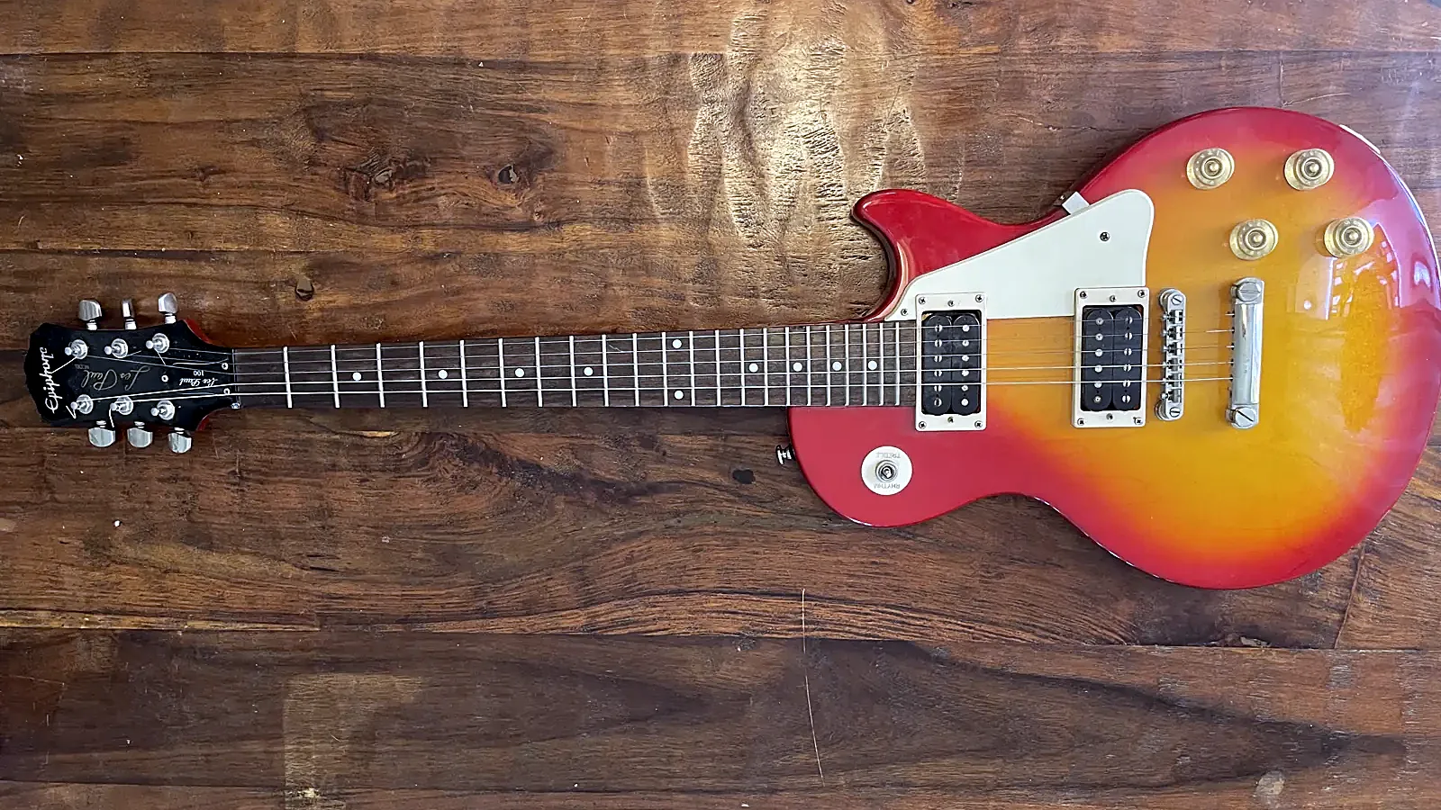 Cherry-sunburst Les Paul-style guitar on a wood bench