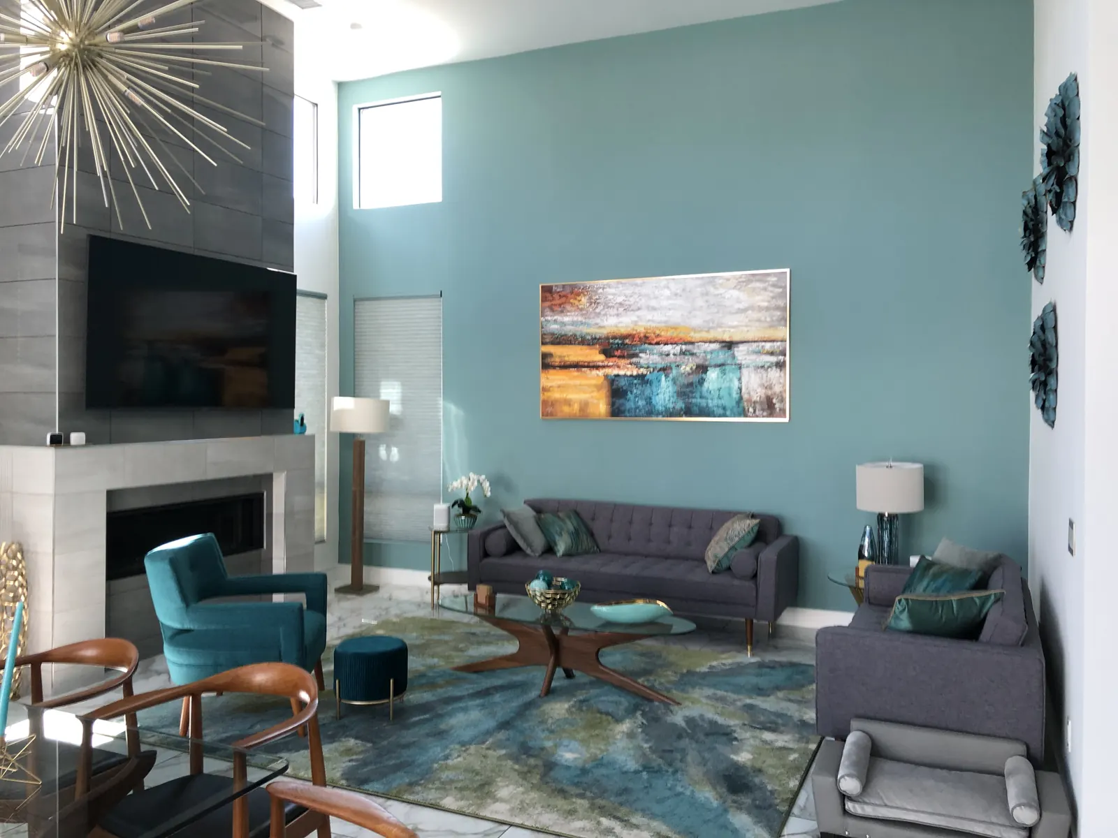 Living room with a teal accent wall and a large canvas hung over the fireplace side
