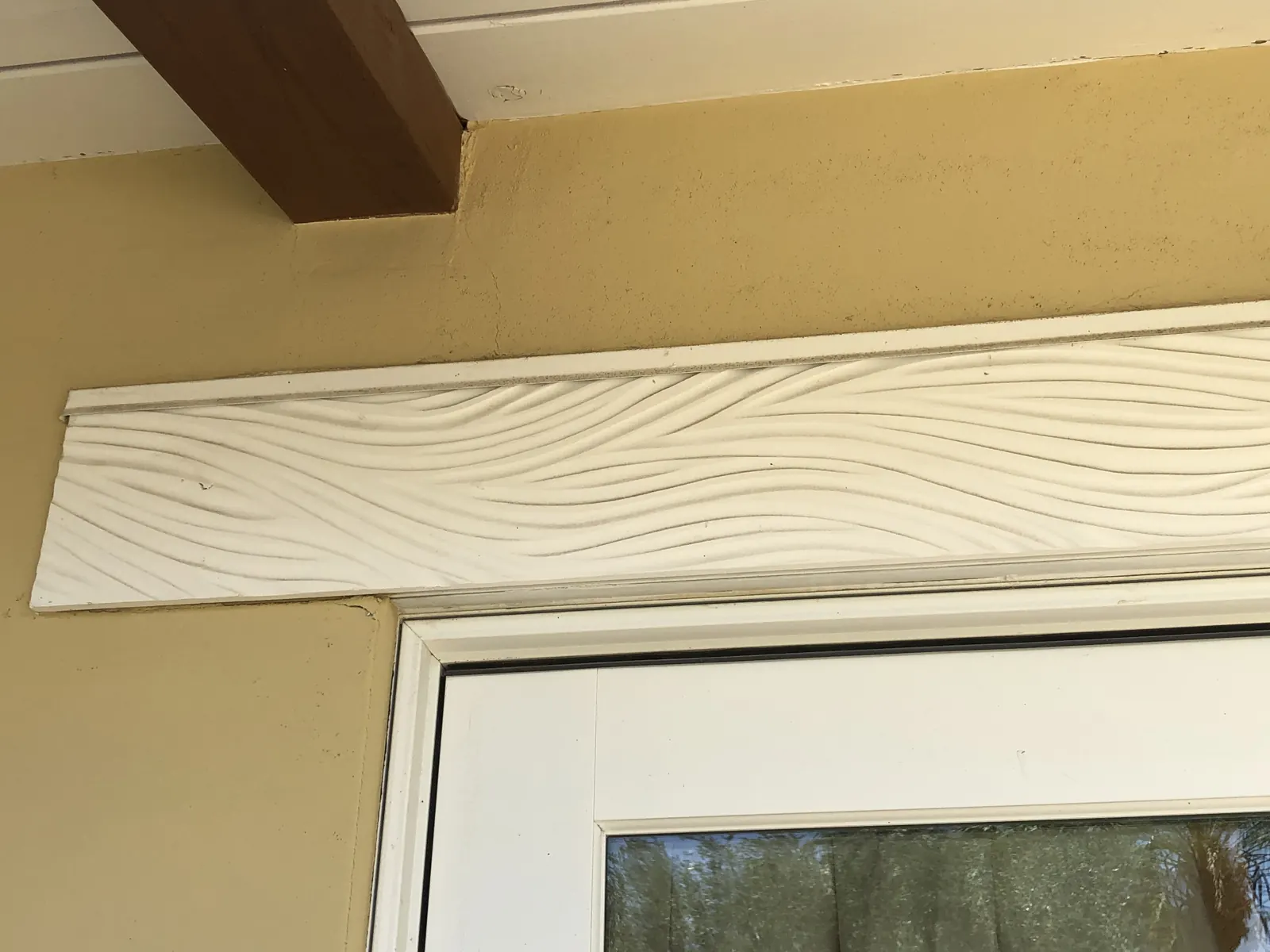 Finished white wave-relief header above a door