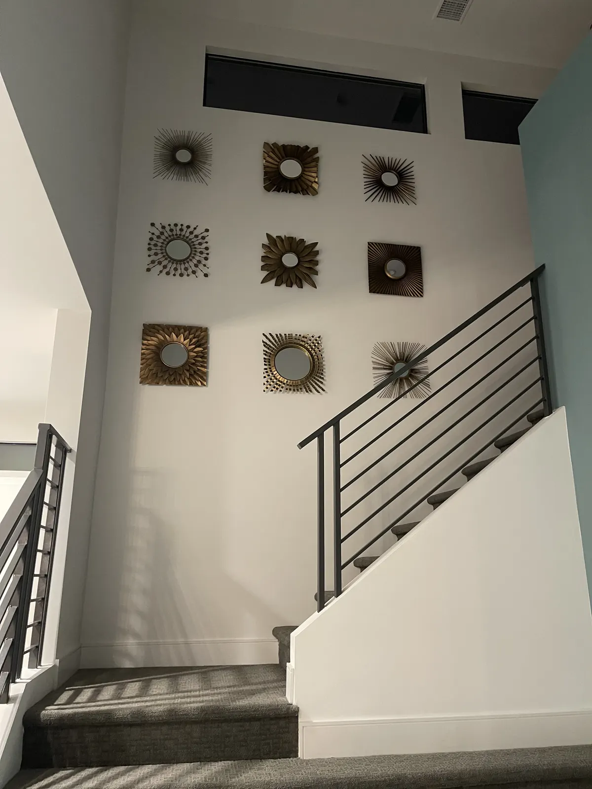 Grid of round wall art pieces climbing a two-story stair wall